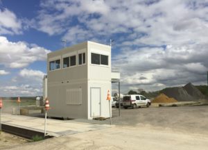 Poste de contrôle modulaire à deux étages sur site industriel avec véhicules utilitaires