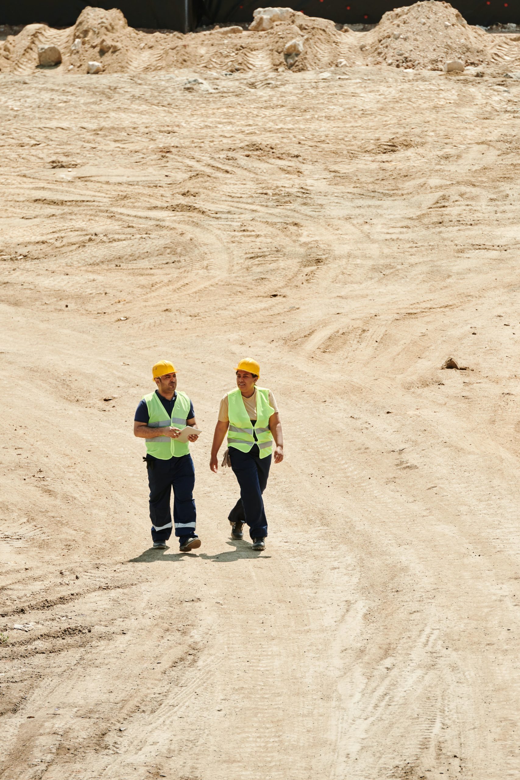 deux responsables de chantier marchent sur les gravas du lieu de chantier avec des équipements de protection
