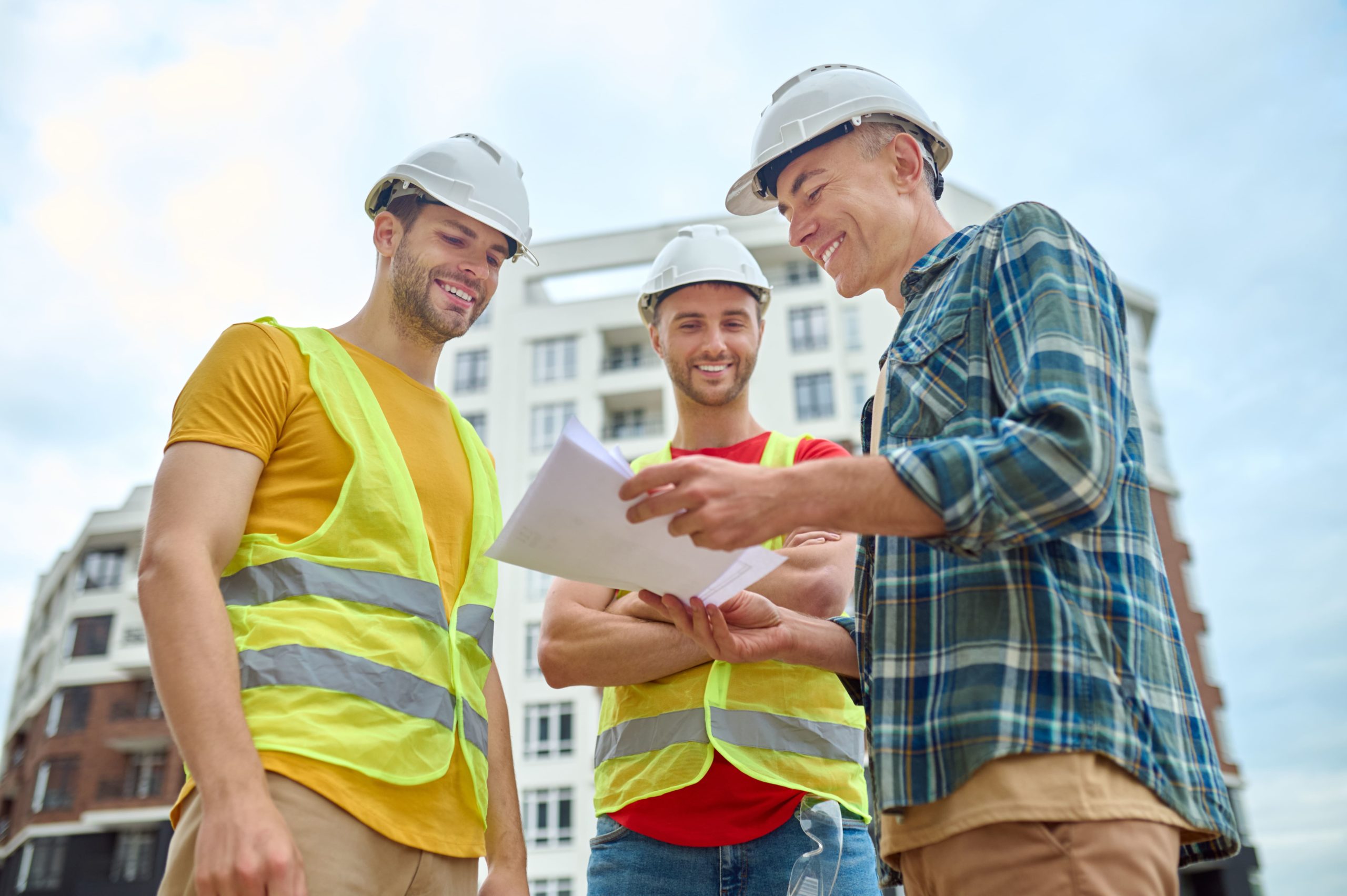Trois ouvriers discutent de la logistique sur un chantier